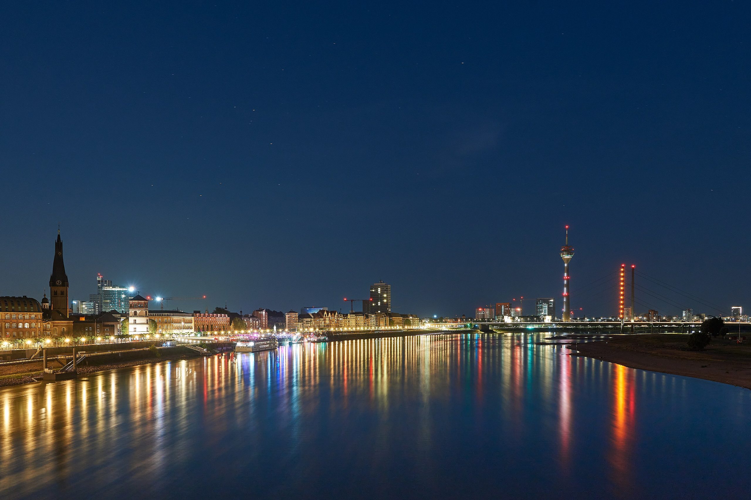 Düsseldorfer Rheinufer zur blauen Stunde mit Altstadt, Rheinturm und Baukränen