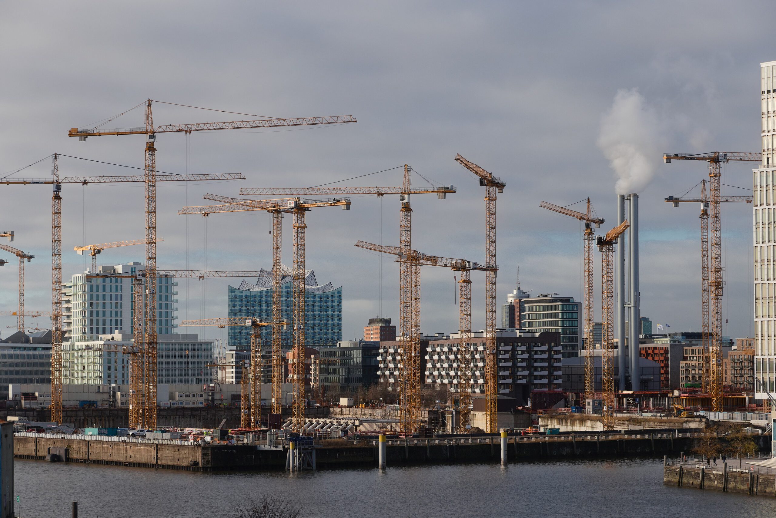 Baukräne über dem Überseequartier in der HafenCity Hamburg, dahinter die Elbphilharmonie