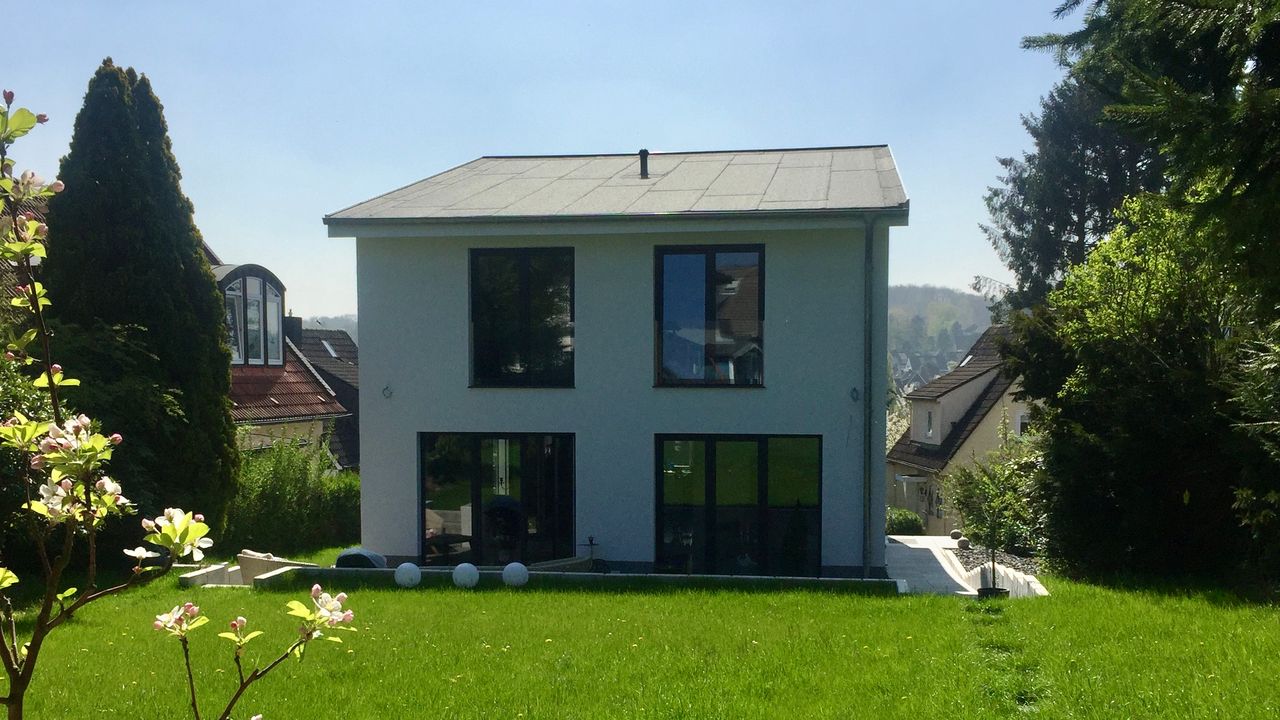 Modernes Einfamilienhaus mit Garten und blühendem Obstbaum