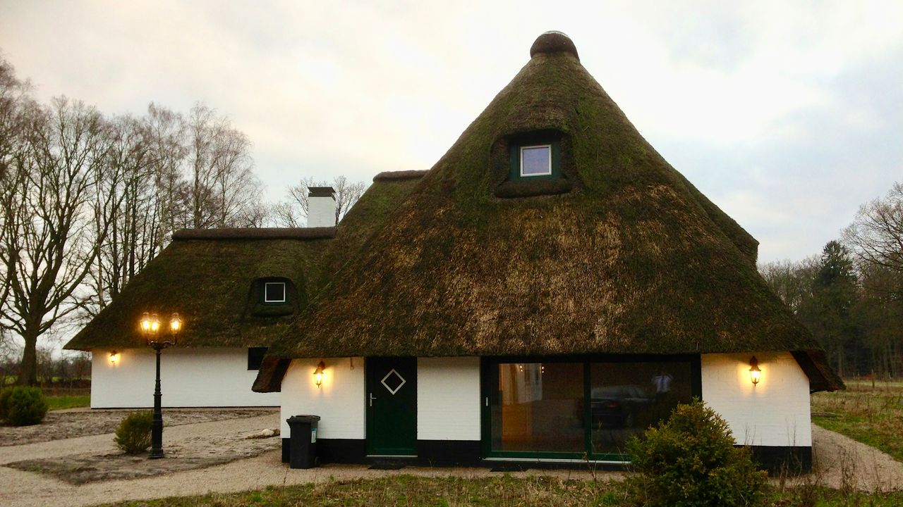 Reetdachhaus in der Abenddämmerung mit Außenleuchten